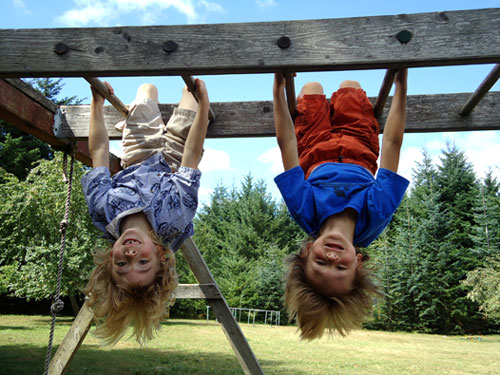 Campers swinging upside down on the monkey bars.